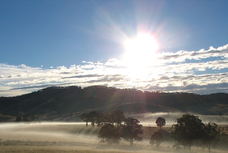 sun shining through clouds over hills